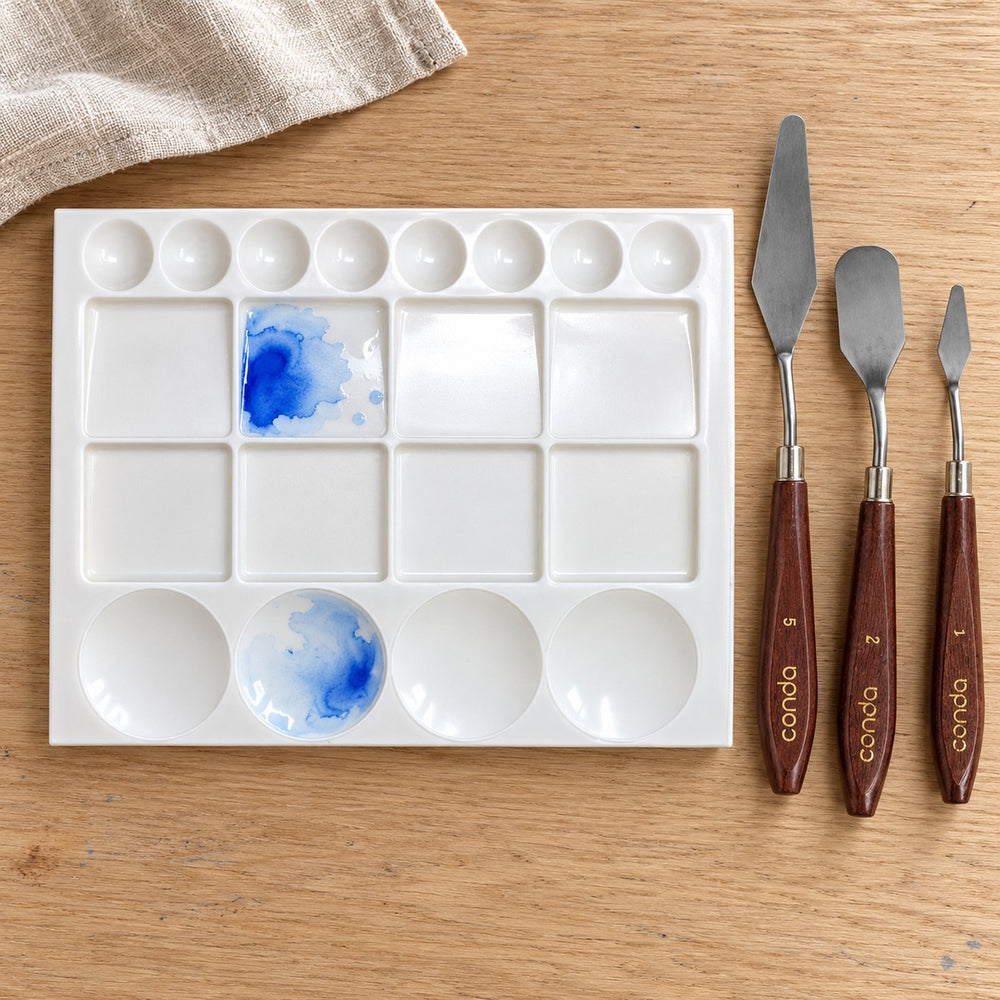 The mixing tray, with 20 wells, beside the palette knives