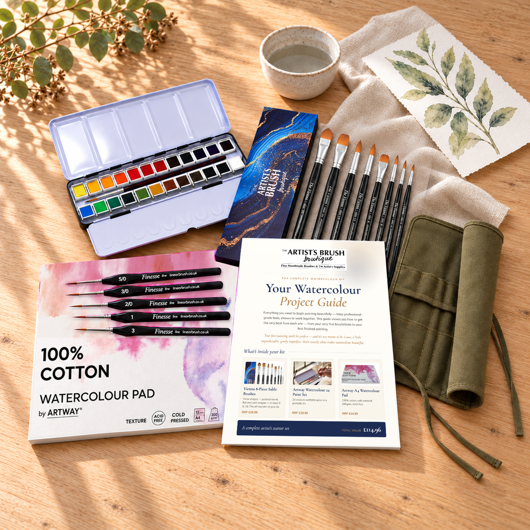 The Complete Watercolour Kit on an oak table: 24 half-pan watercolour tin, Vienna 8-piece sable brush set, 100% cotton A4 watercolour pad, Finesse detail brushes, brush roll and project guide